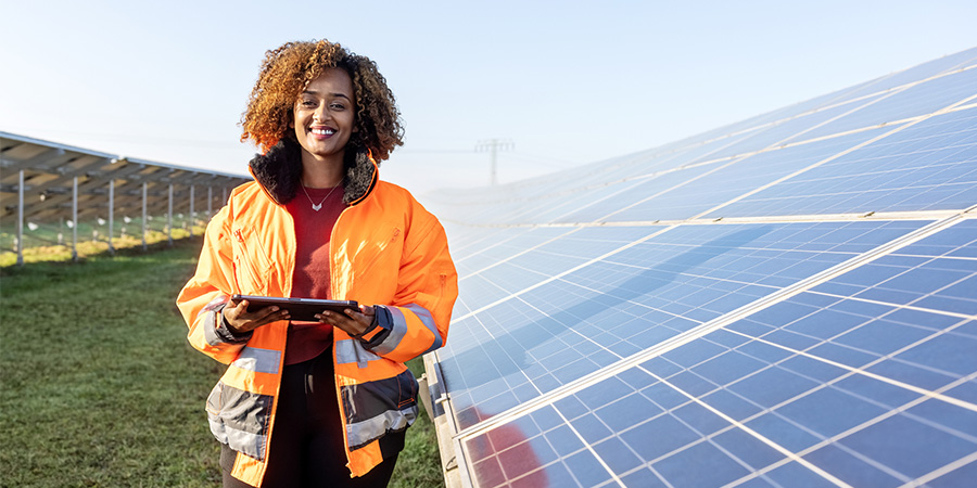 IEEE-USA: Strengthening the Stance of Women in Engineering (Woman in orange jacket, Electrical Engineer, Solar Panel Farm)